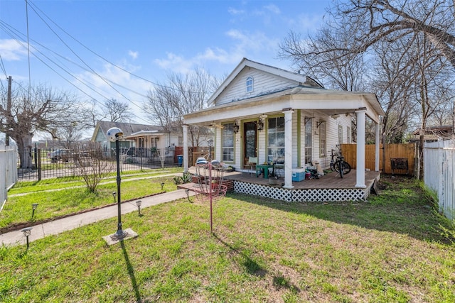 back of property featuring covered porch, a deck, and a yard