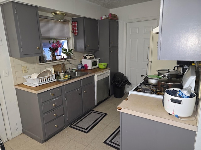 kitchen featuring dishwasher, backsplash, gray cabinetry, and sink