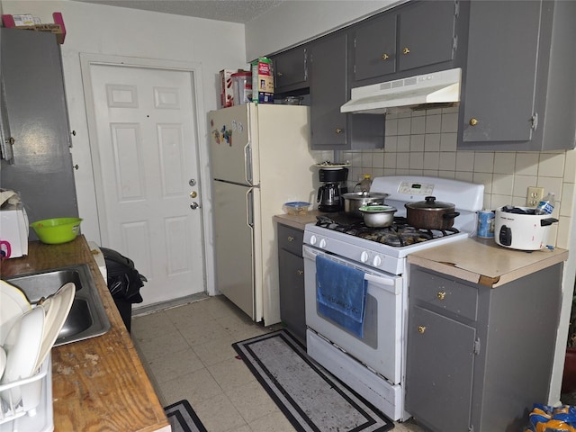 kitchen featuring backsplash, white appliances, gray cabinets, and sink