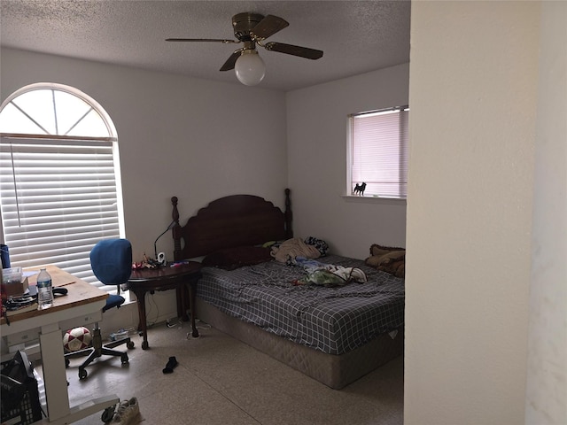 bedroom with ceiling fan and a textured ceiling