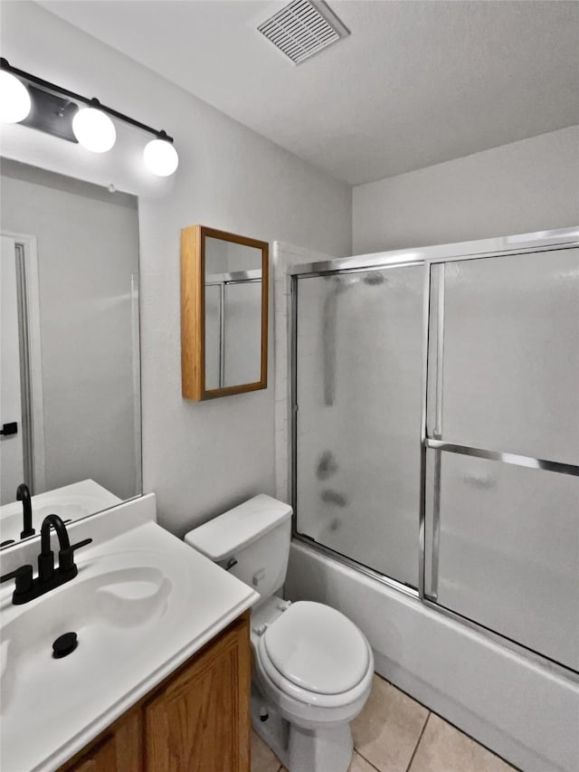 full bathroom with combined bath / shower with glass door, toilet, tile patterned flooring, and vanity