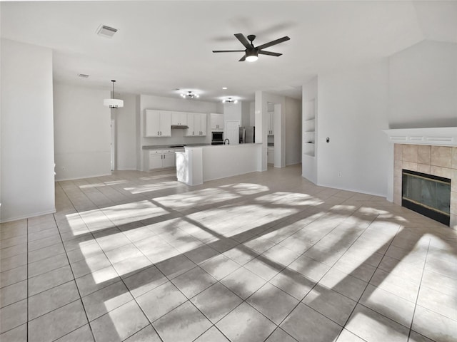 unfurnished living room featuring a tile fireplace, ceiling fan, and light tile patterned flooring