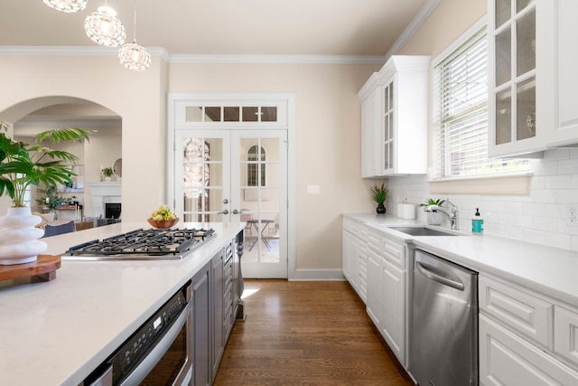 2407 Enfield Rd Unit A, Austin, TX 78703 - kitchen featuring stainless steel appliances, arched walkways, light countertops, white cabinetry, and decorative backsplash