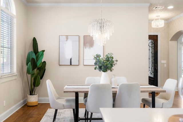 dining area featuring dark hardwood / wood-style floors, crown molding, plenty of natural light, and an inviting chandelier