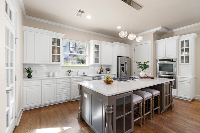 kitchen with a center island, white cabinetry, stainless steel appliances, backsplash, and dark hardwood / wood-style floors