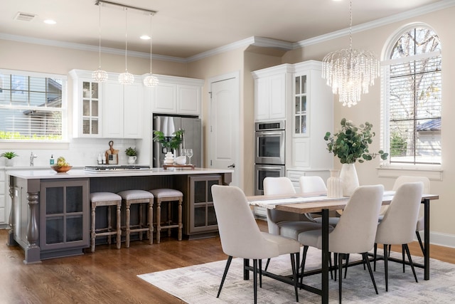 dining area with ornamental molding, a chandelier, track lighting, and dark hardwood / wood-style flooring