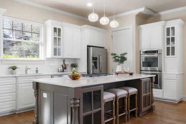 kitchen with pendant lighting, white cabinets, a breakfast bar, a kitchen island, and stainless steel appliances