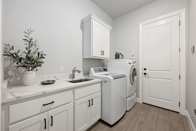 clothes washing area with sink, cabinets, and independent washer and dryer