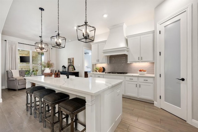 210 Miranda Way, Georgetown, TX 78633 - kitchen with a chandelier, premium range hood, gas cooktop, tasteful backsplash, and white cabinets