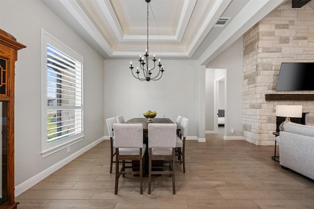 210 Miranda Way, Georgetown, TX 78633 - dining space with a chandelier, wood finished floors, a raised ceiling, and a fireplace