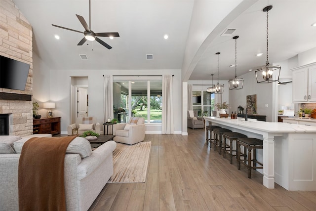 living room featuring a fireplace, light hardwood / wood-style flooring, lofted ceiling, and ceiling fan