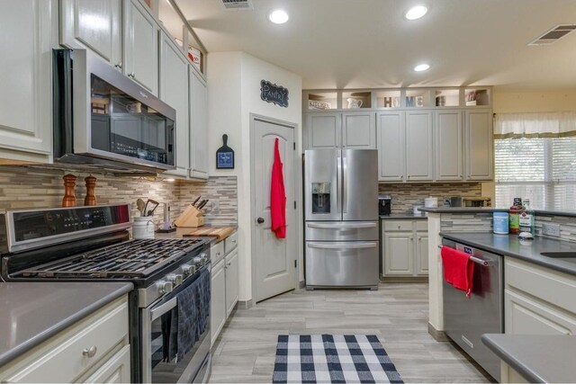 kitchen featuring white cabinets, stainless steel appliances, light hardwood / wood-style floors, and backsplash