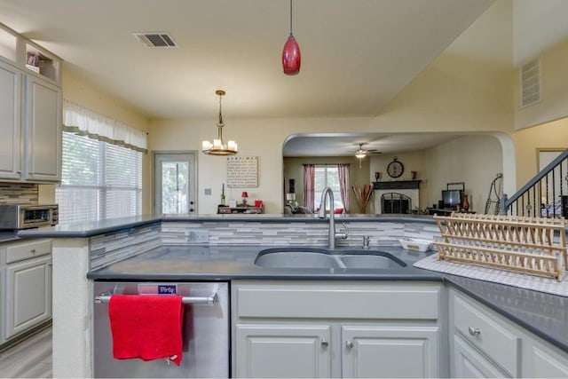 kitchen featuring arched walkways, stainless steel dishwasher, a fireplace, and a sink