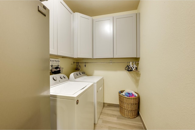 laundry room with separate washer and dryer, cabinets, and light hardwood / wood-style floors