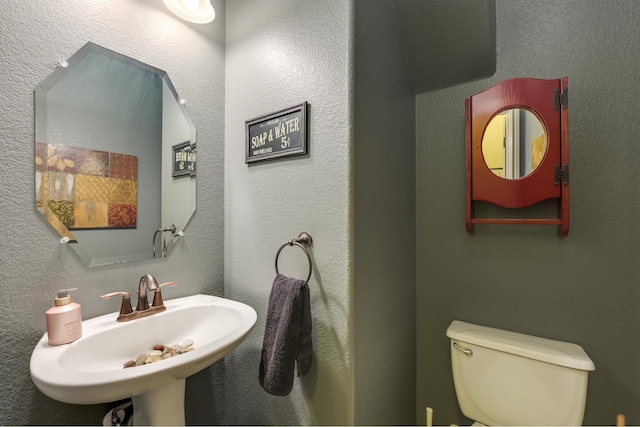 bathroom featuring a textured wall, a sink, and toilet