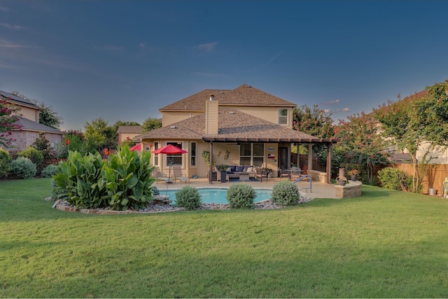 rear view of house with a fenced in pool, outdoor lounge area, a patio, and a lawn