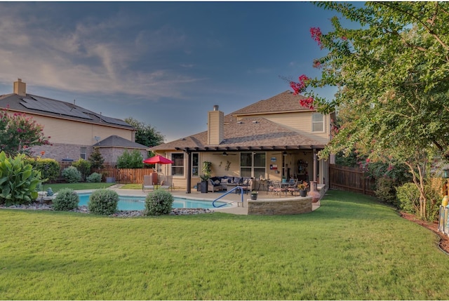 rear view of house with a fenced backyard, a fenced in pool, a lawn, and a patio