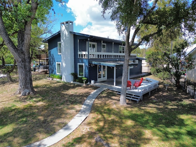 back of property featuring a deck and a lawn