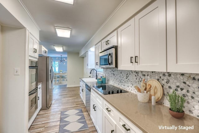 kitchen featuring crown molding, appliances with stainless steel finishes, white cabinets, sink, and backsplash