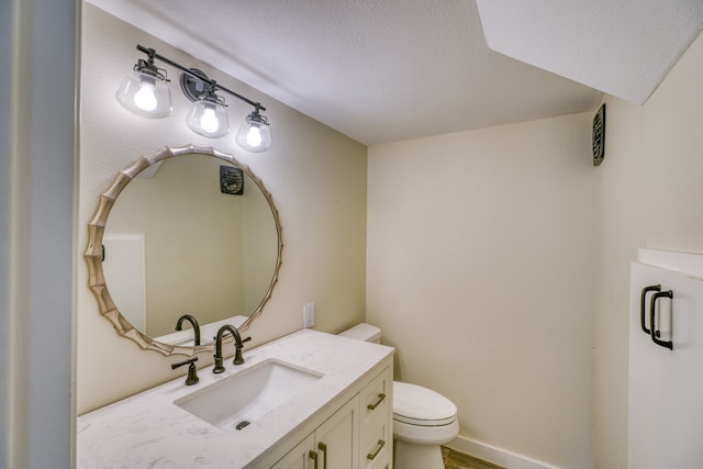 bathroom featuring a textured ceiling, toilet, and vanity