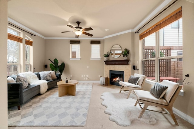 living room with crown molding, ceiling fan, a tile fireplace, and light carpet