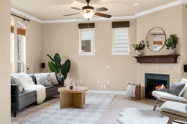 living room with crown molding, ceiling fan, and a tiled fireplace