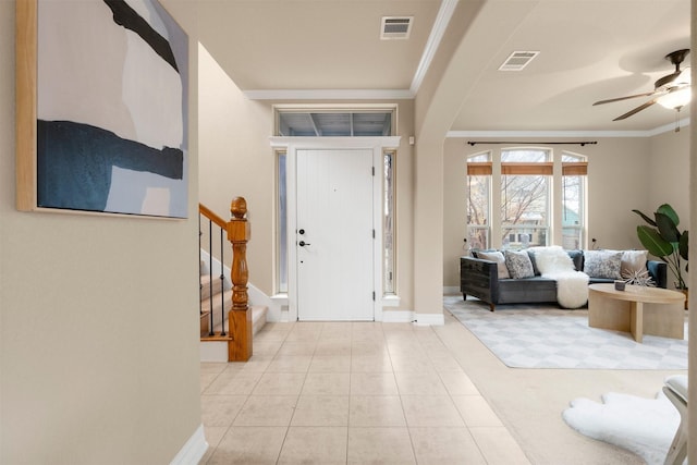 tiled entrance foyer with crown molding and ceiling fan