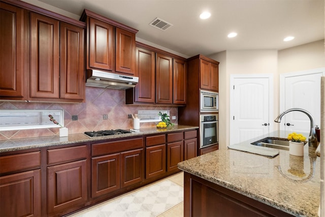 kitchen featuring sink, light stone counters, light tile patterned floors, stainless steel appliances, and decorative backsplash