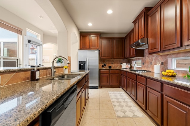 kitchen with sink, light stone counters, light tile patterned floors, stainless steel appliances, and backsplash