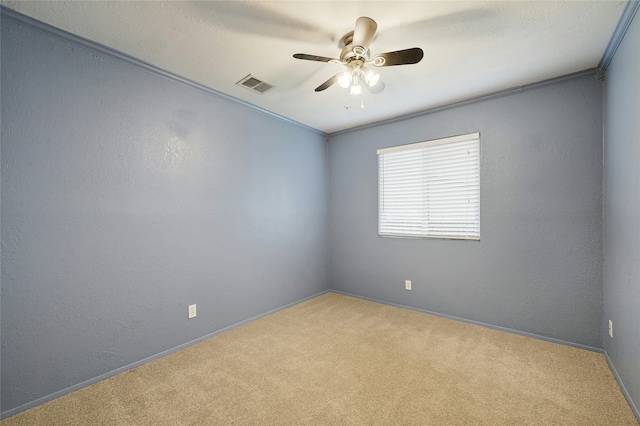 carpeted spare room featuring ceiling fan and ornamental molding