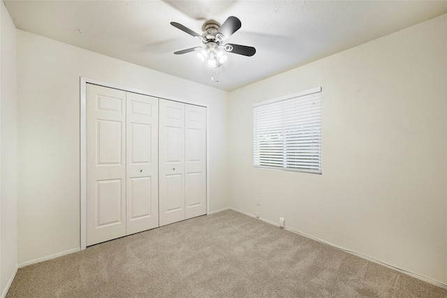 unfurnished bedroom with ceiling fan, a closet, and light carpet