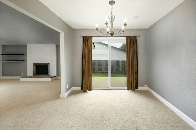 unfurnished dining area featuring an inviting chandelier, light colored carpet, and a fireplace