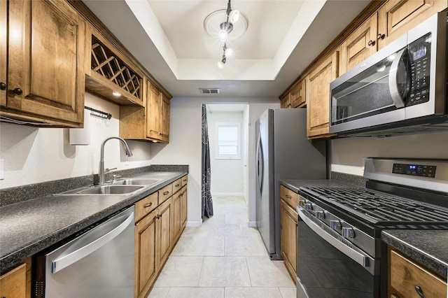 kitchen featuring sink, light tile patterned floors, a tray ceiling, and stainless steel appliances