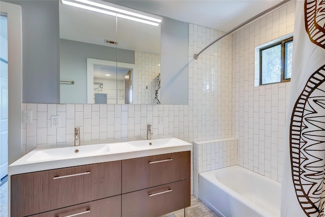 bathroom featuring tile walls, tasteful backsplash, tiled shower / bath, and vanity