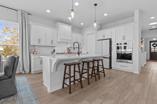 kitchen featuring double oven, hanging light fixtures, white refrigerator, white cabinets, and backsplash