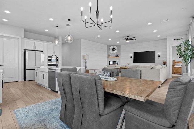 dining space featuring ceiling fan, wooden walls, and light wood-type flooring