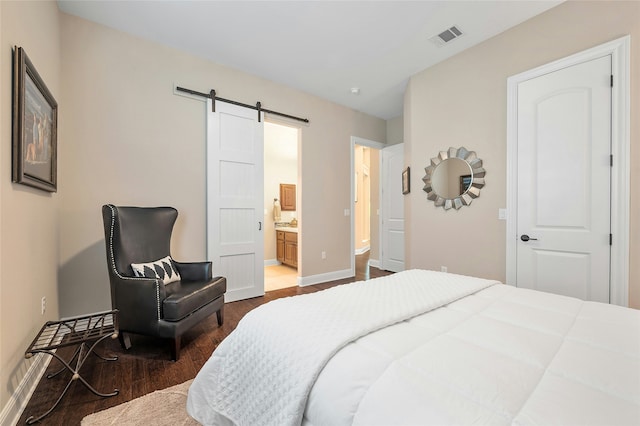 bedroom with connected bathroom, dark hardwood / wood-style floors, and a barn door