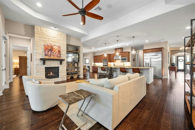 living room featuring ceiling fan, dark hardwood / wood-style floors, built in features, and a fireplace