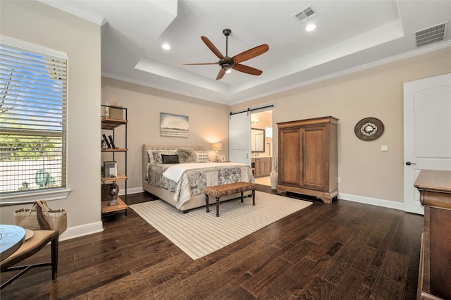 bedroom featuring a barn door, dark hardwood / wood-style floors, ceiling fan, and a raised ceiling