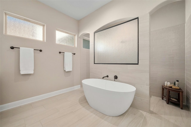 bathroom with tile walls and a bath