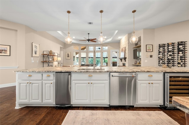 kitchen featuring stainless steel dishwasher, white cabinets, decorative light fixtures, a raised ceiling, and wine cooler