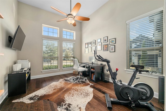 exercise area with ceiling fan and dark wood-type flooring