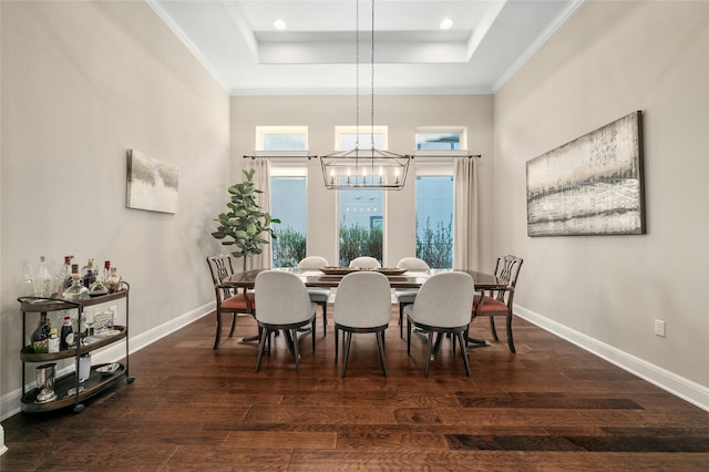 dining area with dark wood-type flooring, a chandelier, a raised ceiling, and a towering ceiling