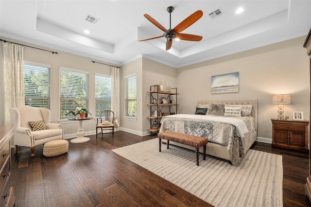 bedroom with ceiling fan, a tray ceiling, dark hardwood / wood-style floors, and crown molding