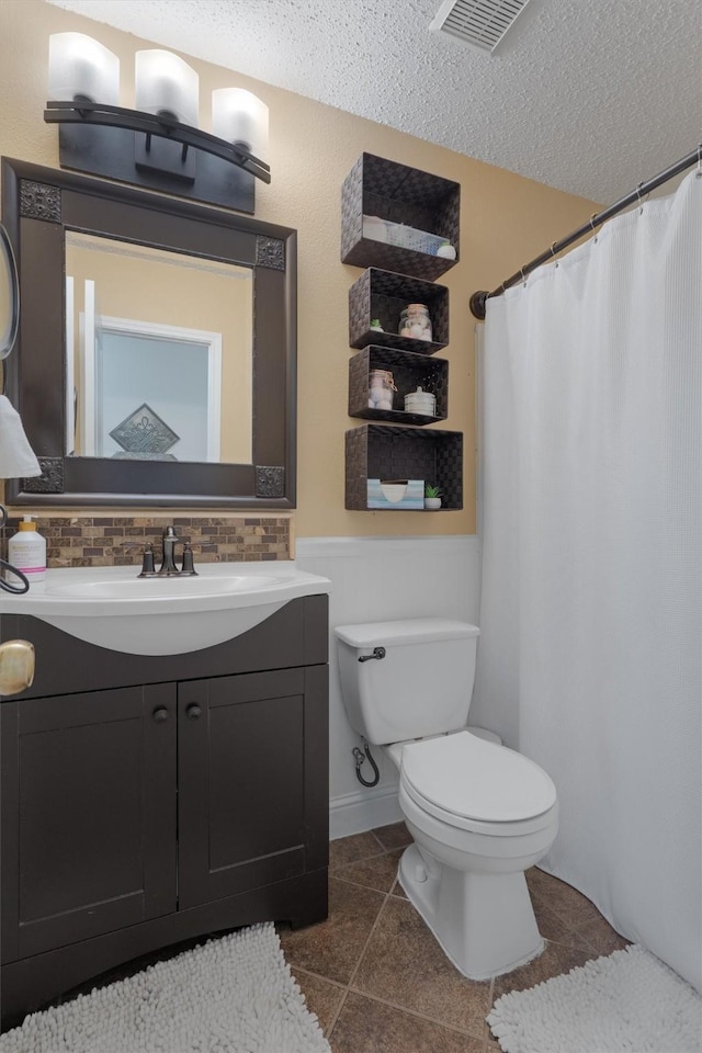 bathroom featuring tile patterned flooring, backsplash, a textured ceiling, toilet, and vanity