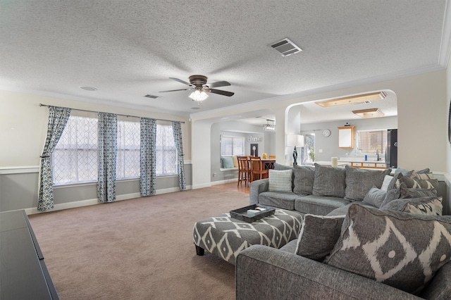 carpeted living room featuring a textured ceiling, ceiling fan, and ornamental molding