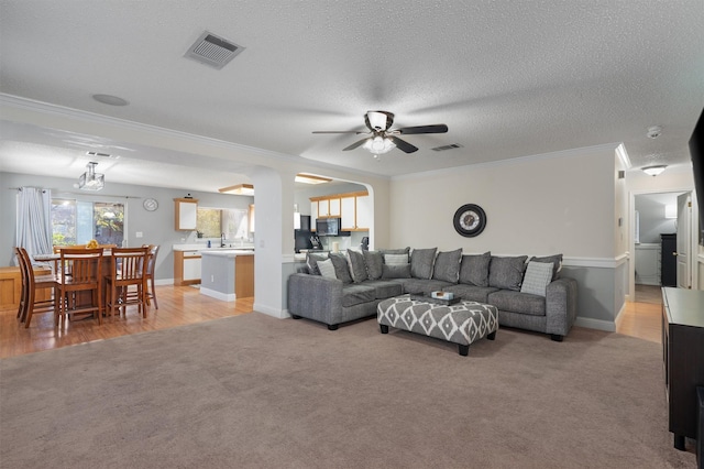 carpeted living room featuring crown molding, a textured ceiling, and ceiling fan