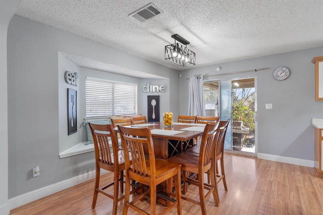 dining space with light hardwood / wood-style floors and a textured ceiling