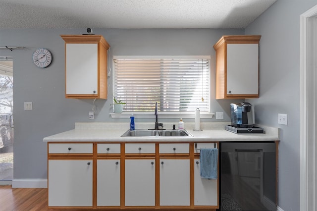 kitchen with sink, light wood-type flooring, white cabinetry, and a textured ceiling