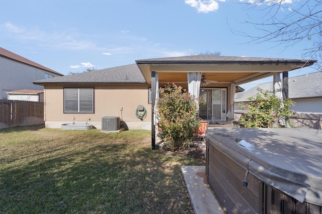 back of house with ceiling fan, central AC unit, a lawn, and a hot tub